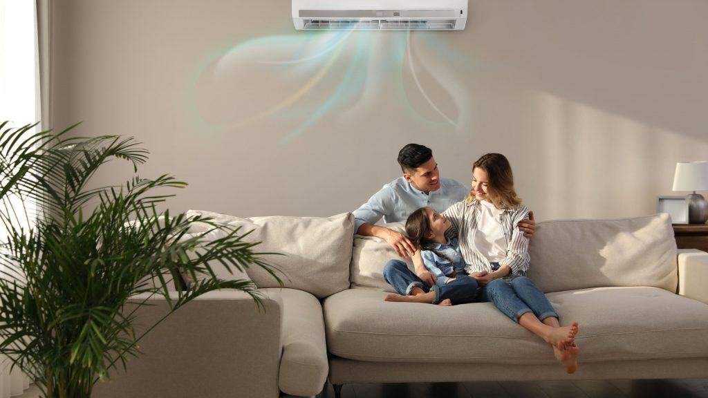 Family sitting on the room with the air conditioning on top of the wall