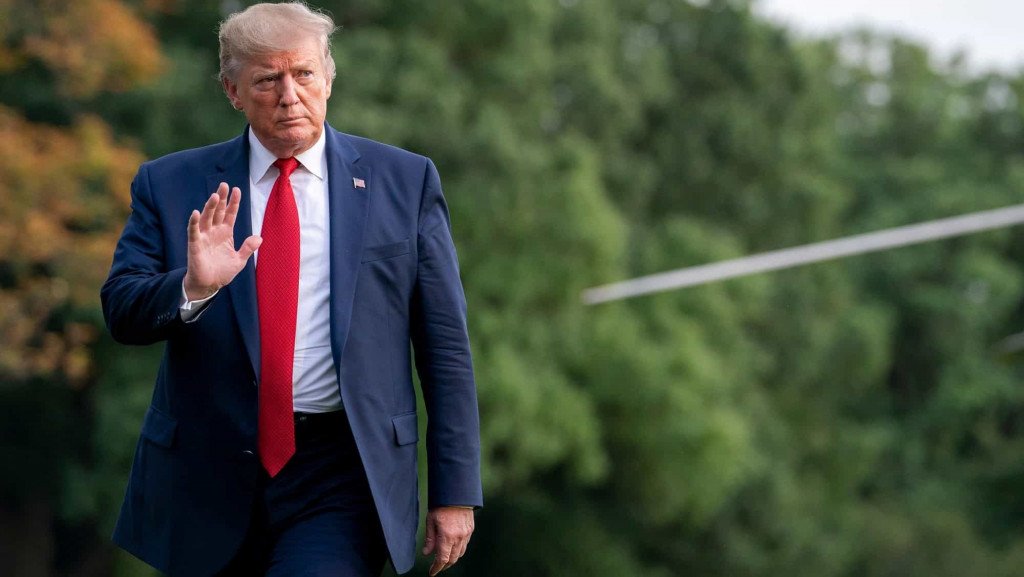Donald Trump with his hand raised while walking
