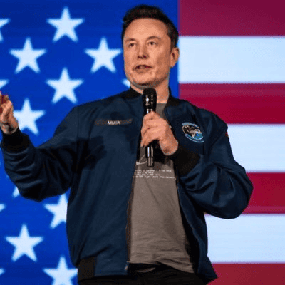Elon Musk speaking; behind, the flag of the United States